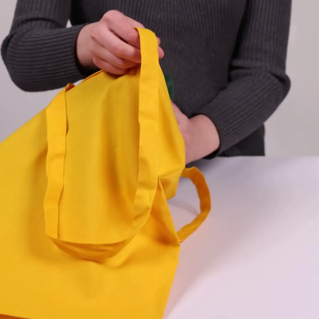 Bomuldspose, 140 g/m², vist af en person i produktvideoen – gul