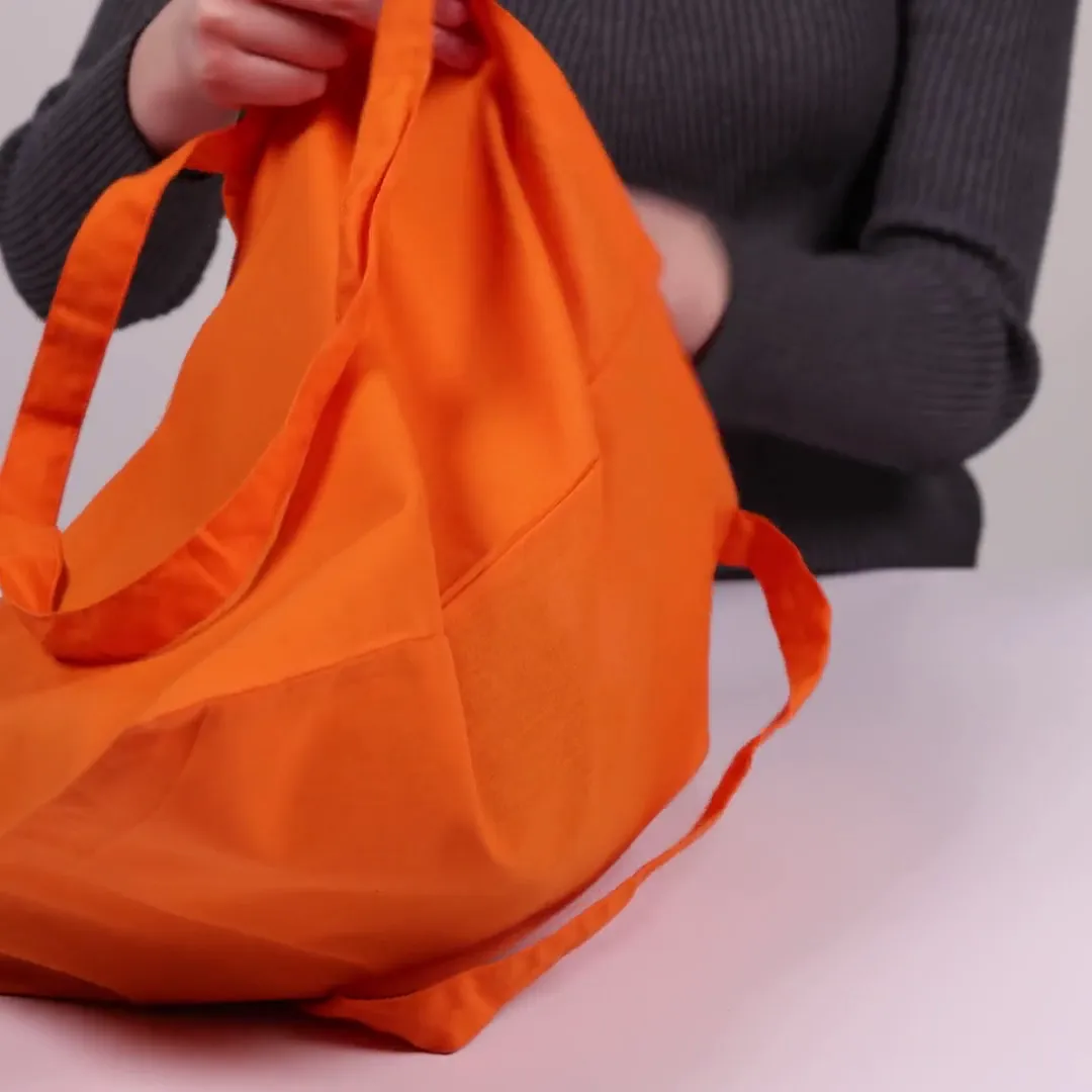 Bomuldspose, 140 g/m², vist af en person i produktvideoen – orange