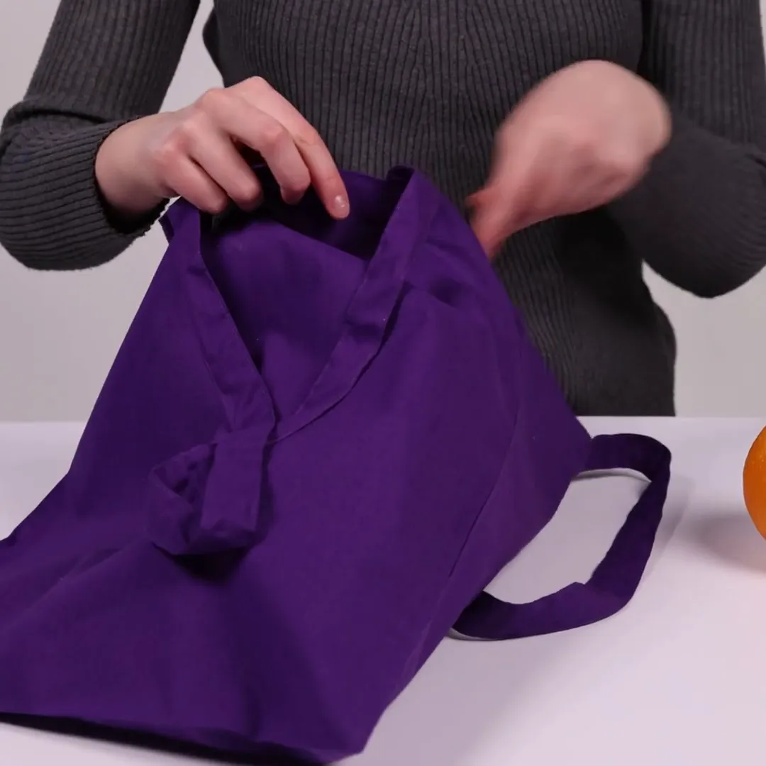 Bomuldspose, 140 g/m², vist af en person i produktvideoen – violet