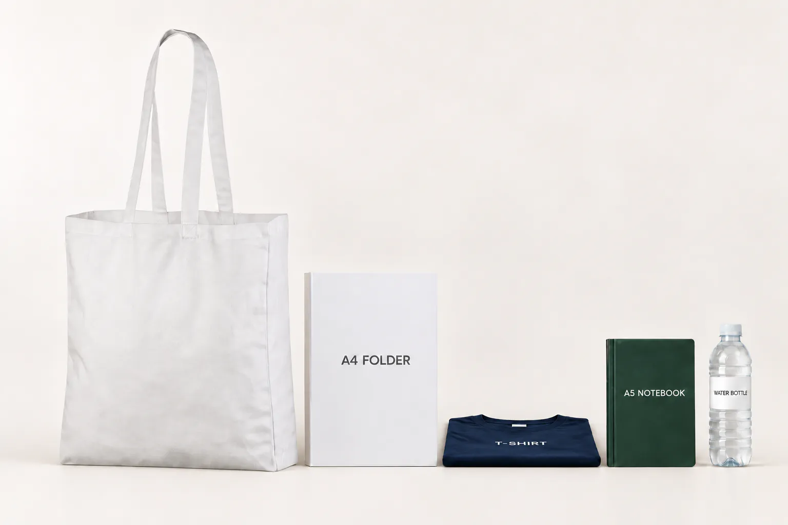 Hvid bomuldspose med fals ved siden af en A4-mappe, en foldet T-shirt, en A5-notesbog og en drikkeflaske.