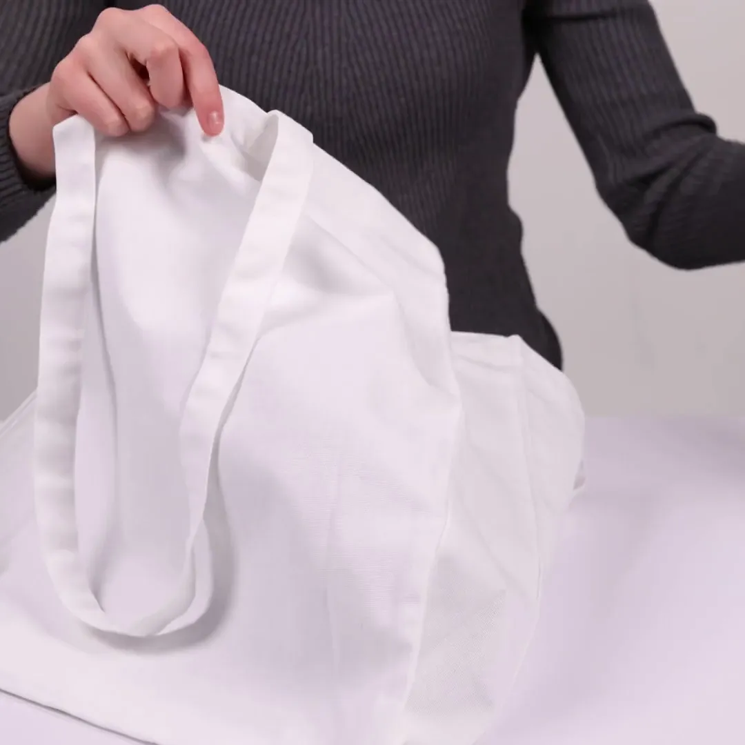 Bomuldspose med fals, 220 g/m², vist af en person i produktvideoen – hvid