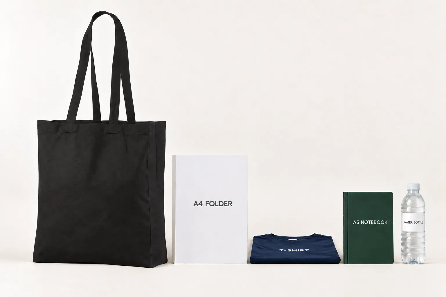 Sort bomuldspose med fals ved siden af en A4-mappe, en foldet T-shirt, en A5-notesbog og en drikkeflaske.