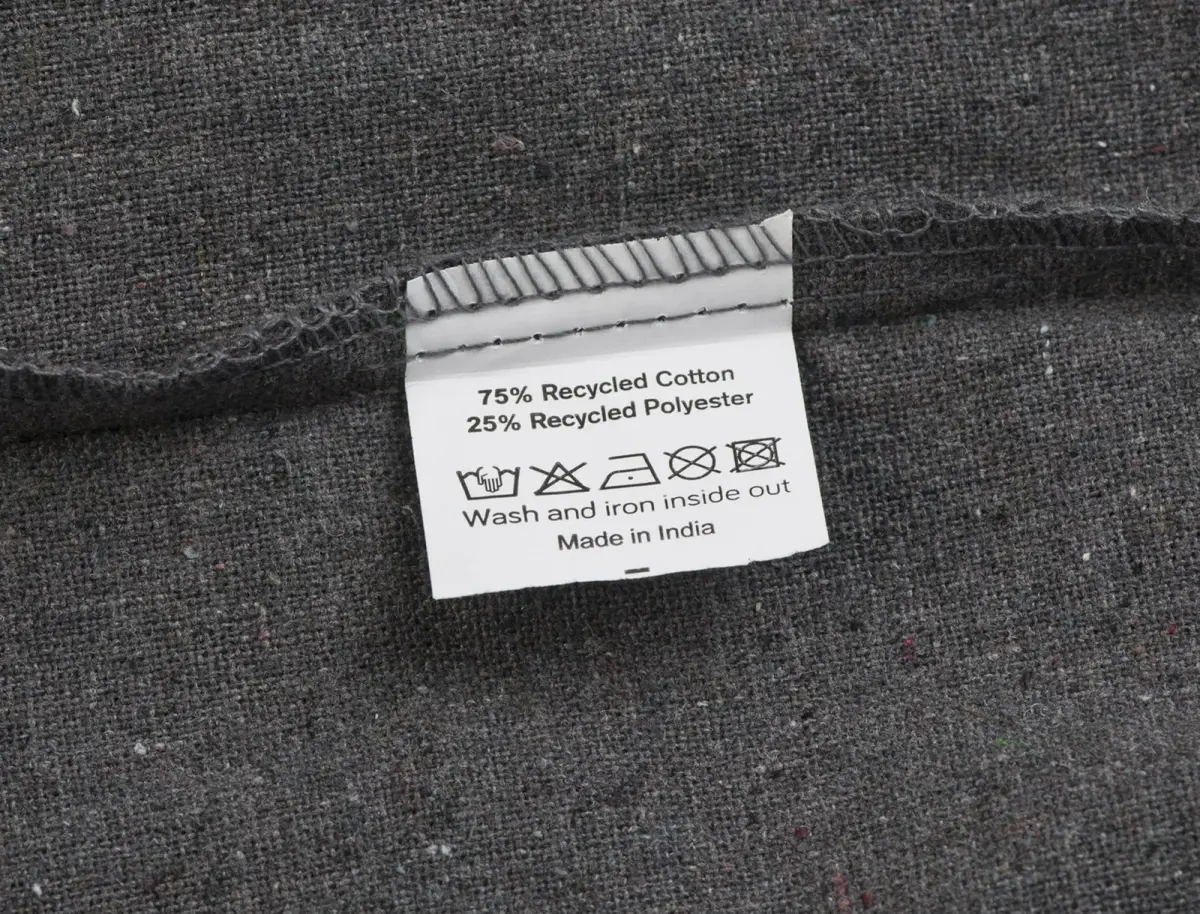 Mulepose – etiket med 75 % genanvendt bomuld, 25 % genanvendt polyester og vaskesymboler.